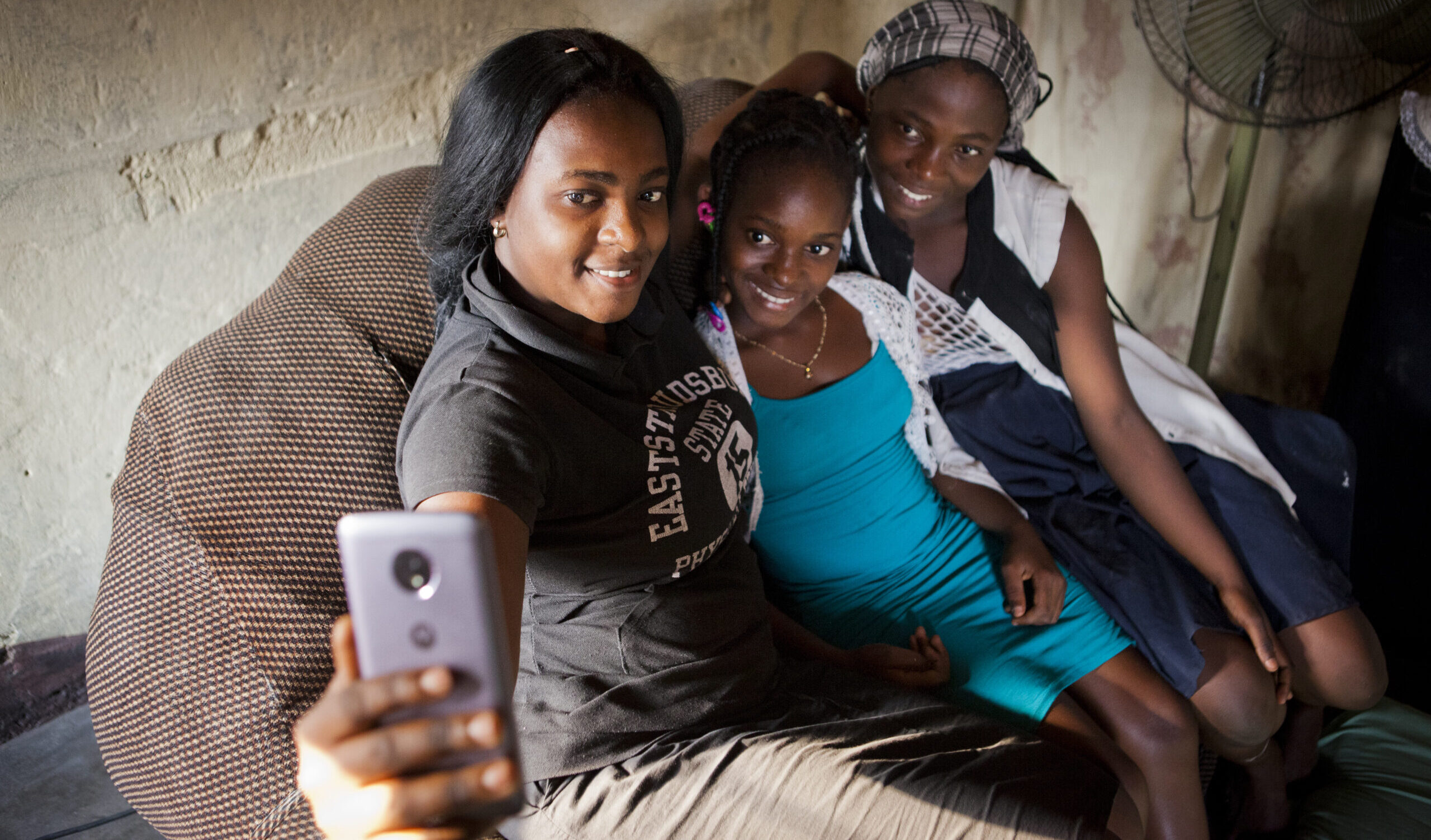 Obride Mpayikilu is at home,with her sister and cousin, they are taking a selfie all together.
