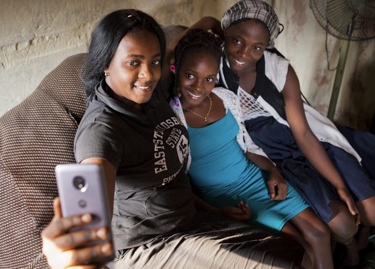 Obride Mpayikilu is at home,with her sister and cousin, they are taking a selfie all together.